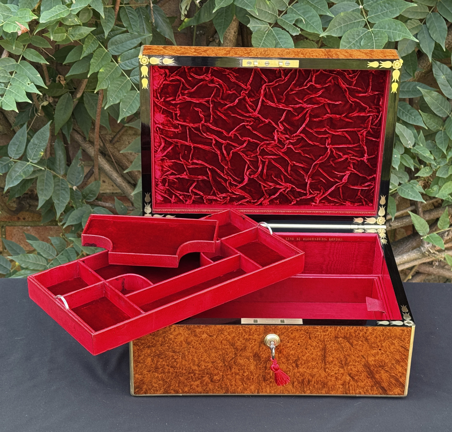 Front overhead interior view of an antique jewellery box in amboyna, by Edwards, with both top trays removed.