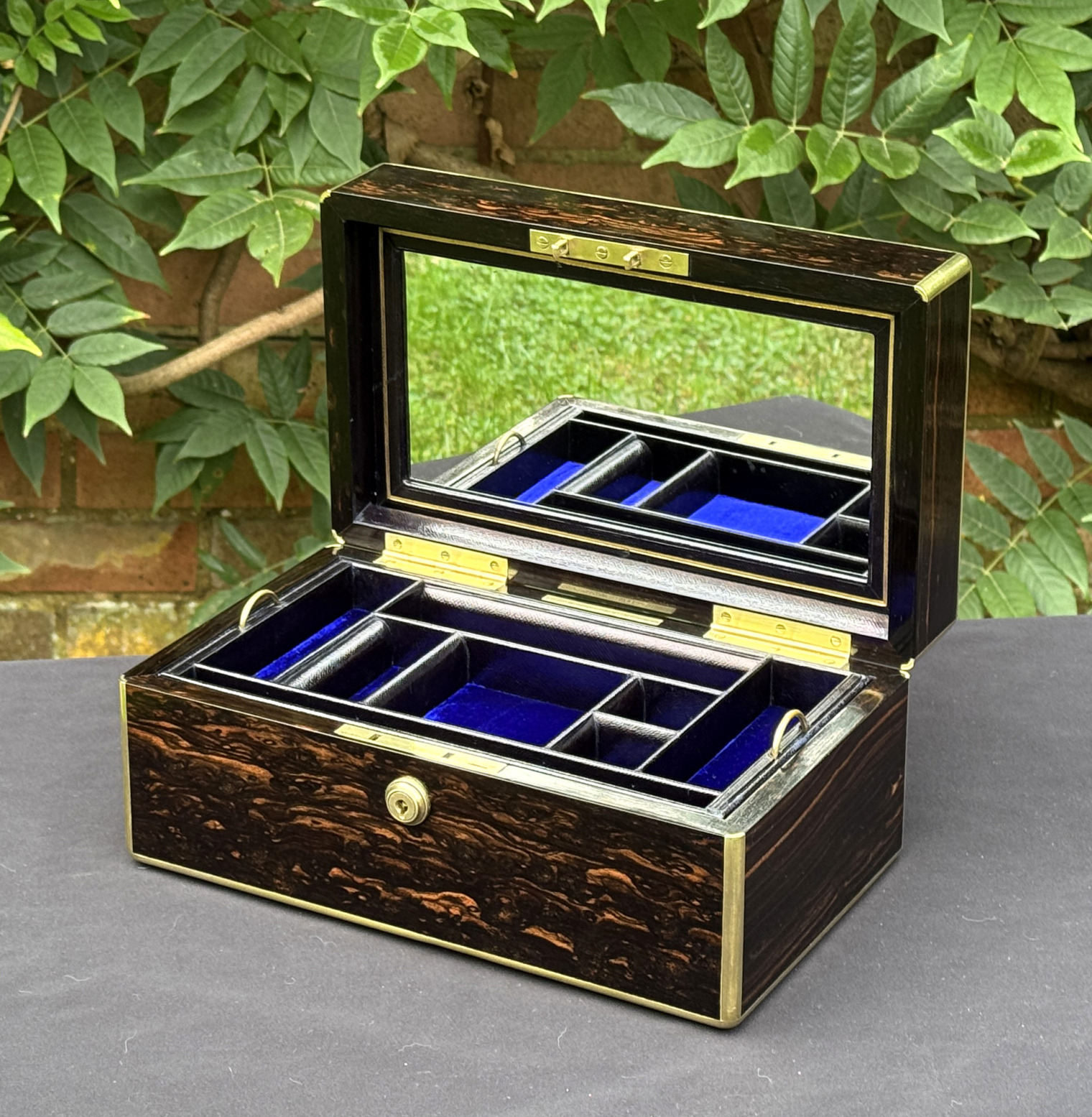 Front right internal view of an antique gentleman's travelling jewellery box in coromandel, by Houghton & Gunn, with mirror panel on display.