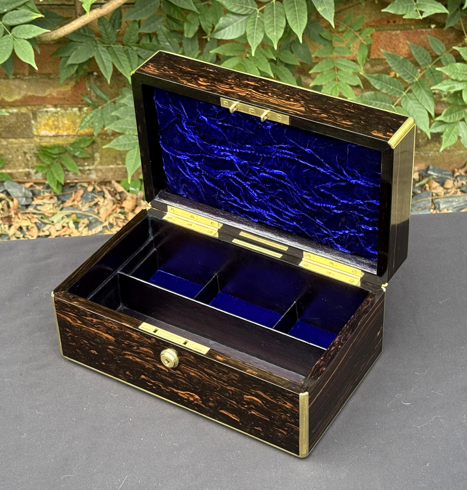 Overhead internal view of an antique gentleman's travelling jewellery box in coromandel, by Houghton & Gunn, with jewellery tray fully removed.