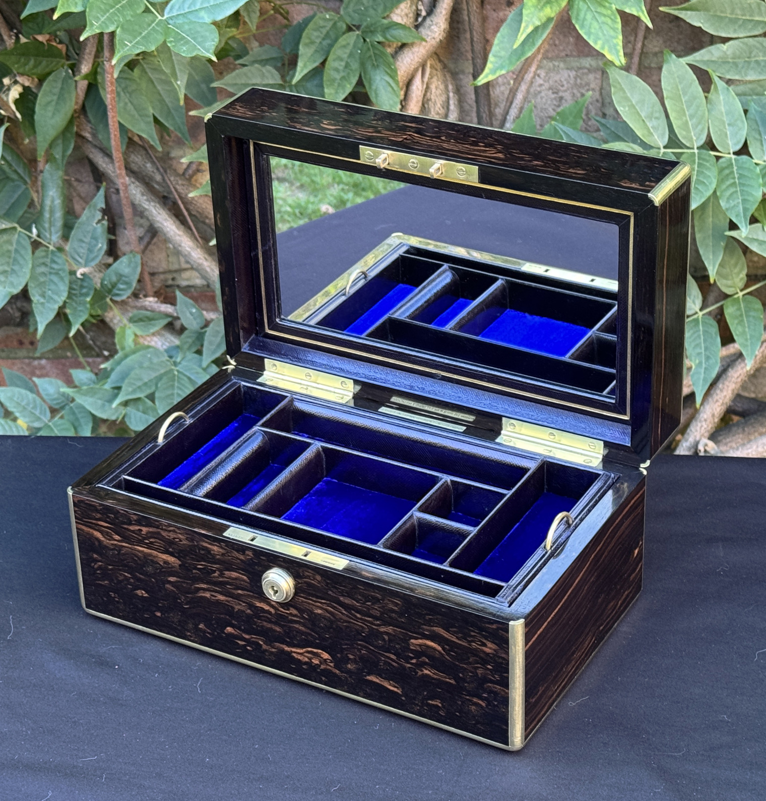 Front right internal view of an antique gentleman's travelling jewellery box in coromandel, by Houghton & Gunn, with mirror panel on display.