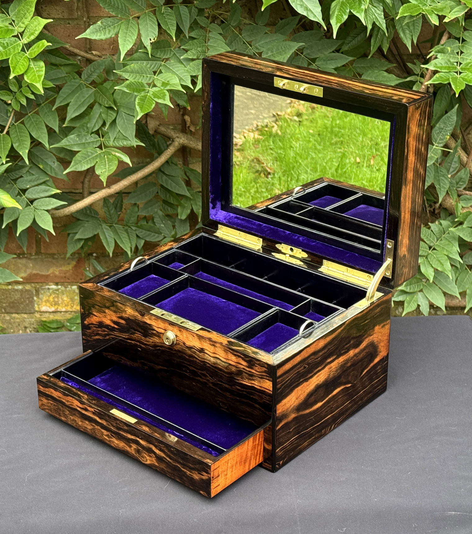 Front right interior view of an antique jewellery box in calamander, by George Betjemann & Sons, with lower drawer extended and mirror panel on display.