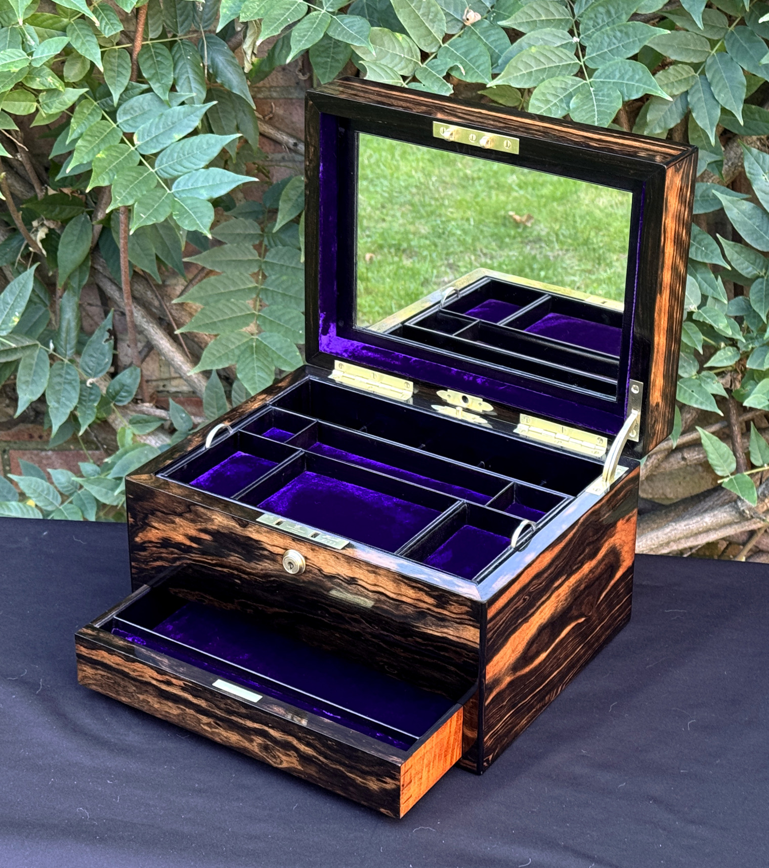Front right interior view of an antique jewellery box in calamander, by George Betjemann & Sons, with lower drawer extended and mirror panel on display.