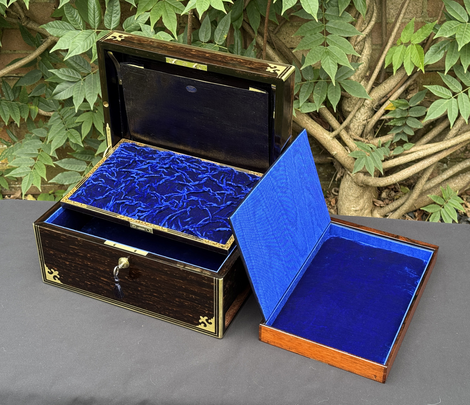 Front right interior view of an antique jewellery box in coromandel, by Thomas Dalton, with side drawer removed and its hinged-lid opened, and the concealed leather letter wallet on display.