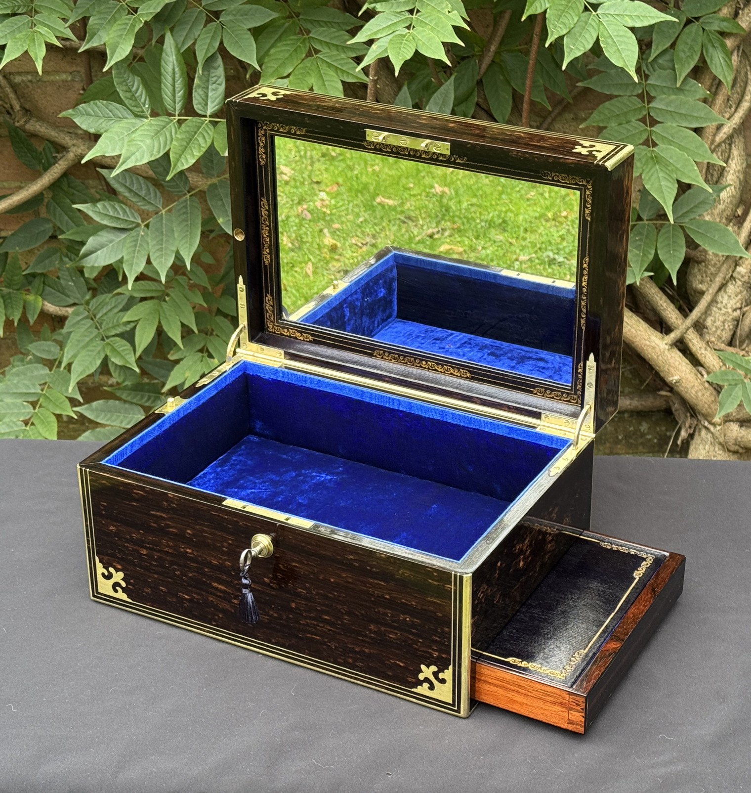 Front right interior view of an antique jewellery box in coromandel, by Thomas Dalton, with side drawer partially extended and mirror panel on display.