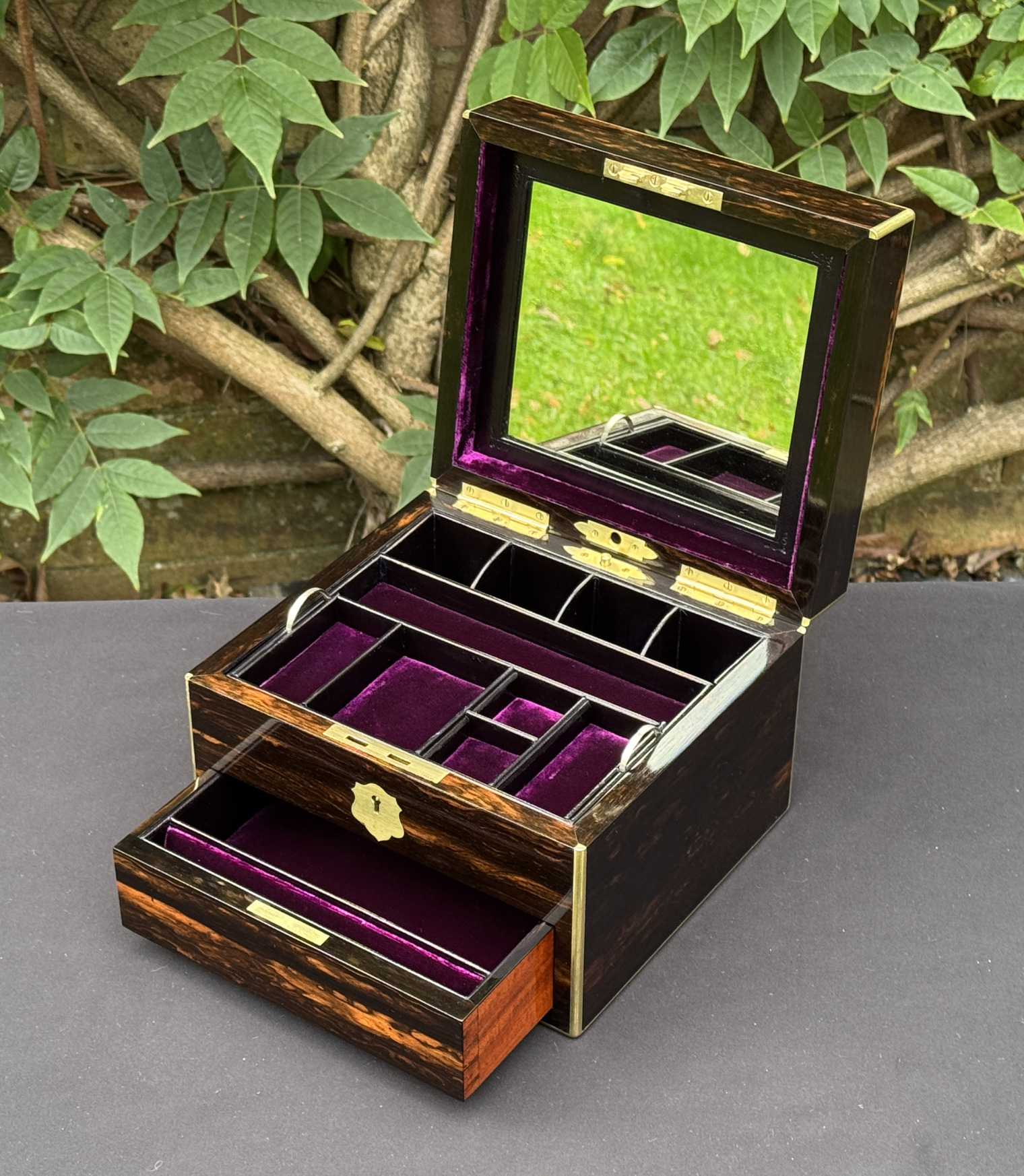 Front right interior view of a miniature antique jewellery box in coromandel, by George Betjemann & Sons, with lower drawer extended and mirror panel on display.