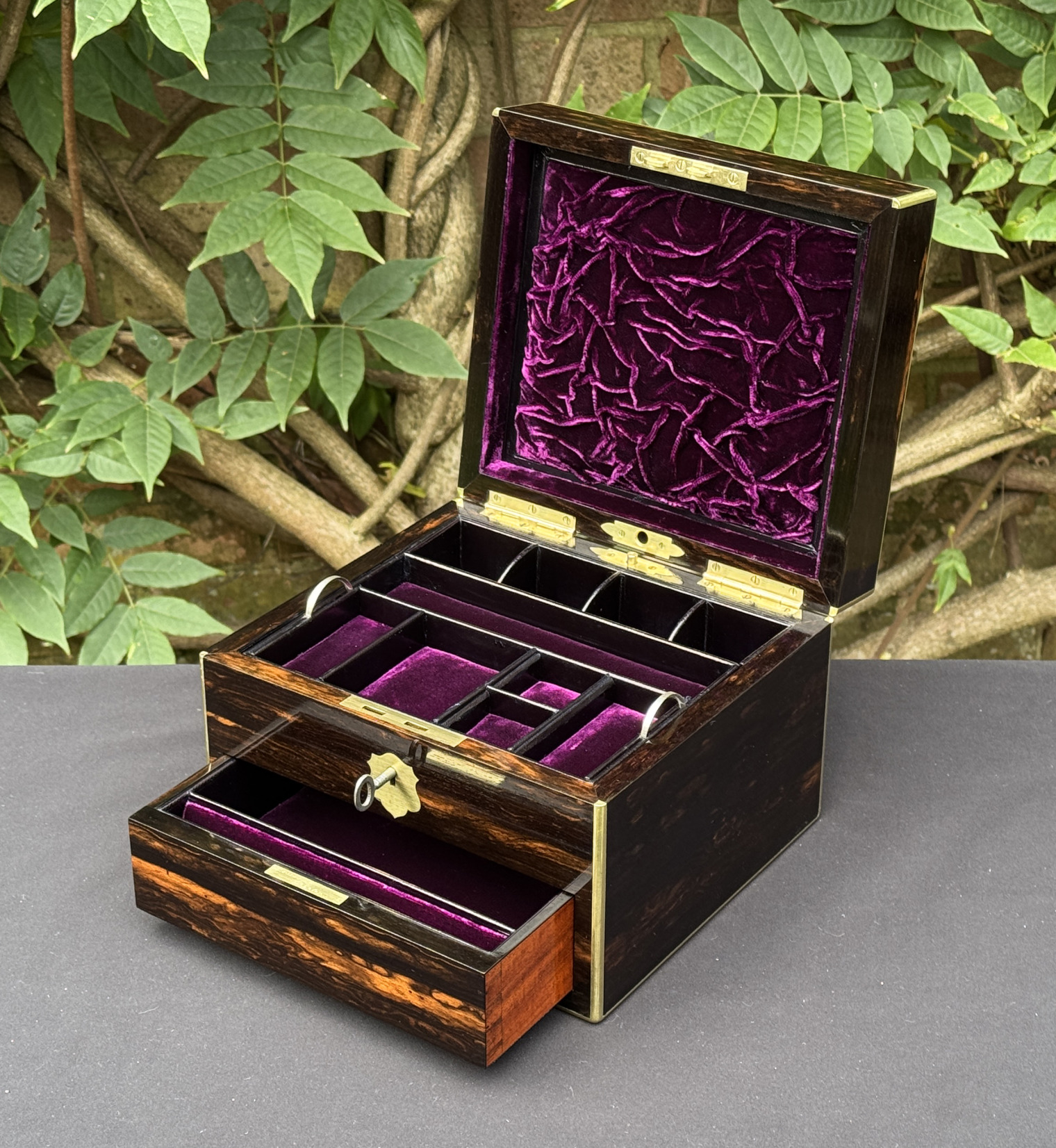 Front right interior view of a miniature antique jewellery box in coromandel, by George Betjemann & Sons, with lower drawer extended and key inserted.