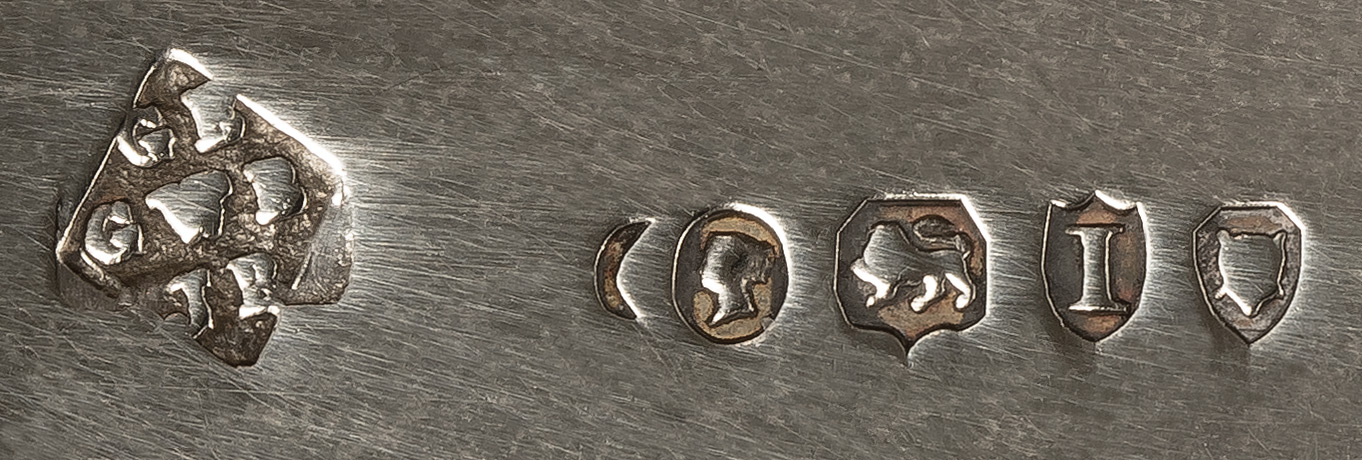 George Betjemann and Sons Silver Hallmark. The ‘GB’ refers to George Betjemann, the ‘GWB’ refers to George William Betjemann, and the ‘JB’ refers to John Betjemann. Looking at the date letter ‘I’ tells us that this silver dressing case jar lid dates to 1884.