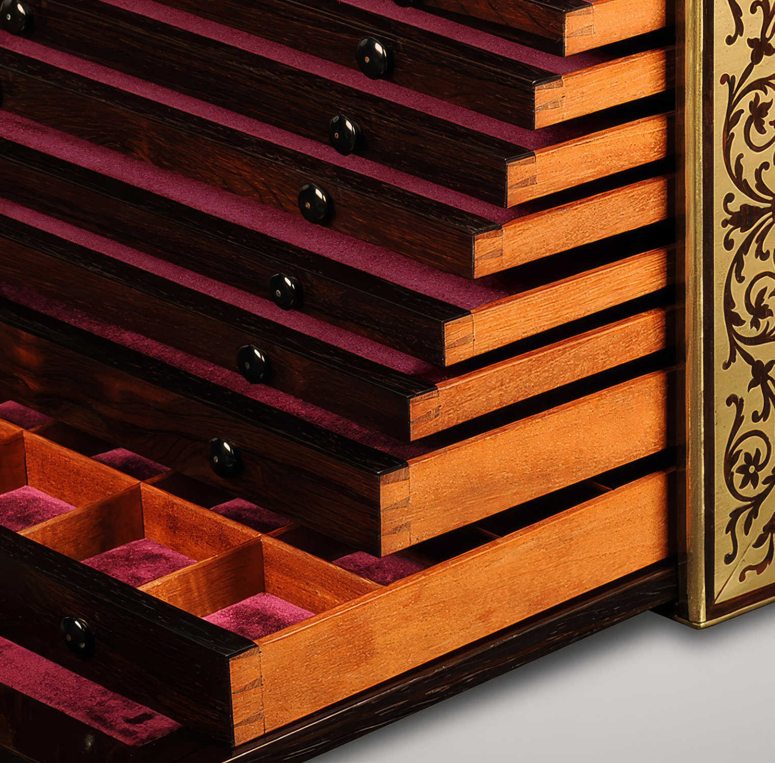 Close-up of stacked dovetail-joined drawers in a rosewood jewellery cabinet with foliate brass inlay.