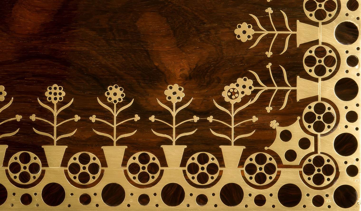 Close-up of geometric and floral brass inlay on a rosewood jewellery box.