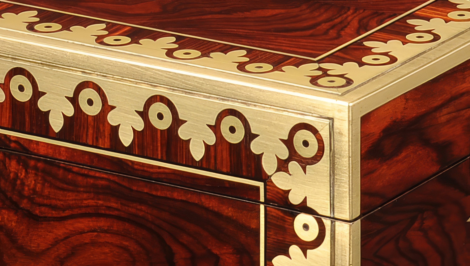 Close-up of brass inlay and brass edging at the corner of a kingwood jewellery box.
